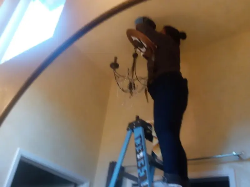 Electrician installing a chandelier in a Carmel residence
